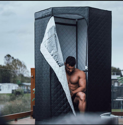 A man sitting inside the AuraPro portable steam sauna, relaxing and enjoying a peaceful wellness session at home.